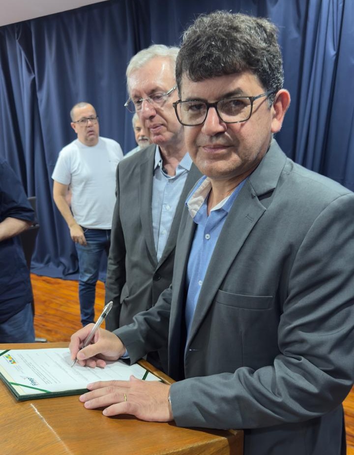 UFRRJ Parque Ecotecnológico foto mostra professor roberto, reitor da universidade rural, em pose após assinar o termo, sendo observado pelo presidente da finep, celso pancera