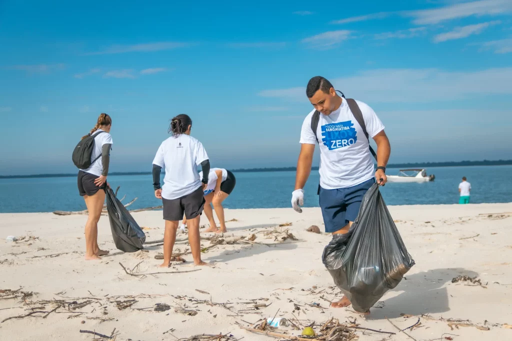 Pessoas recolhendo lixo da areia da praia