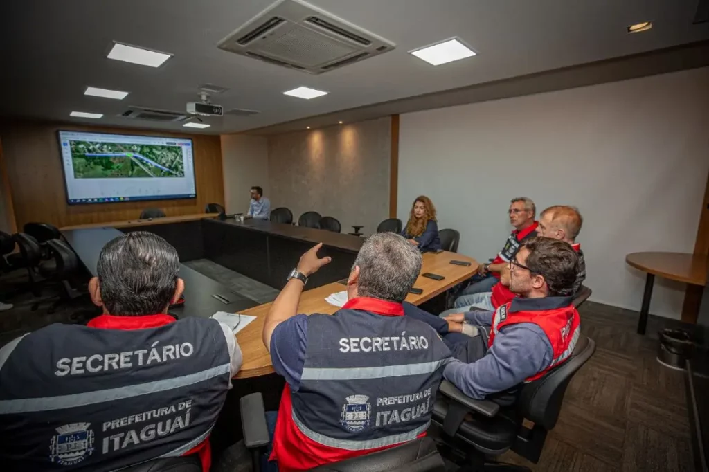 Homens sentados à mesa assistindo a um vídeo
