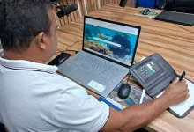 Homem no computador e com calculadora e caneta à mão
