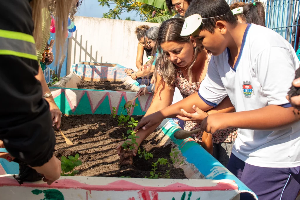 Aluno ajudado no plantio de uma muda de planta