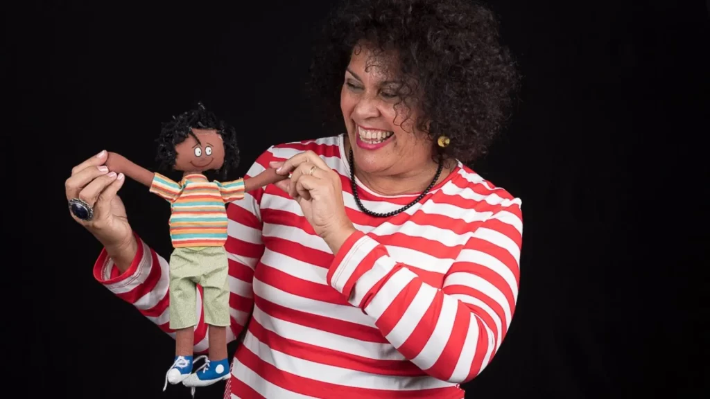 Escritora Sonia Rosa segura boneco infantil, referência de sua literatura negro-afetiva celebrada no MUHCAB.