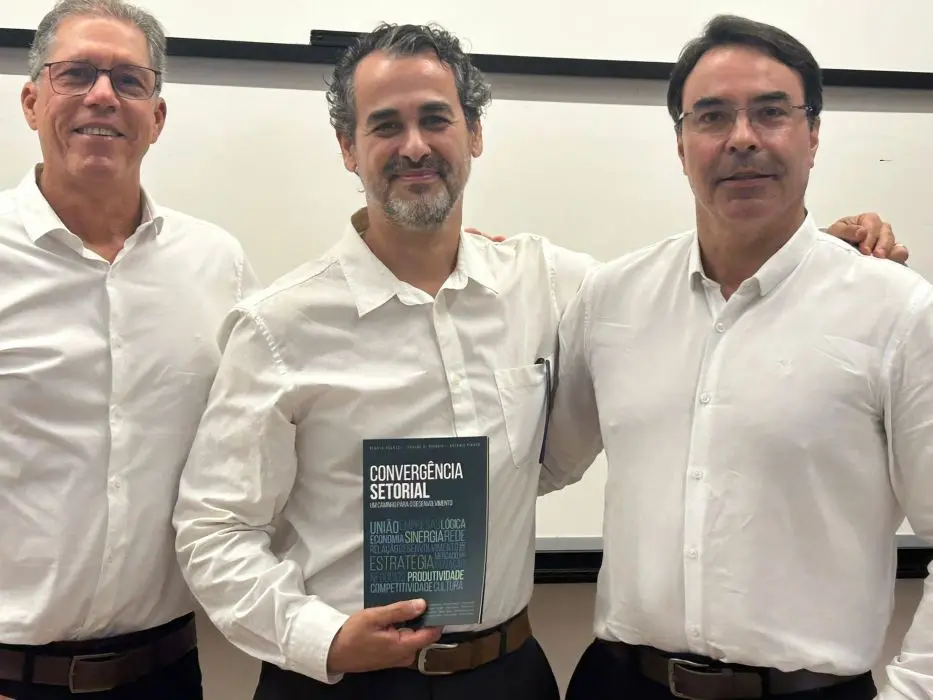 Os autores do livro ladeando um convidado que segura um exemplar