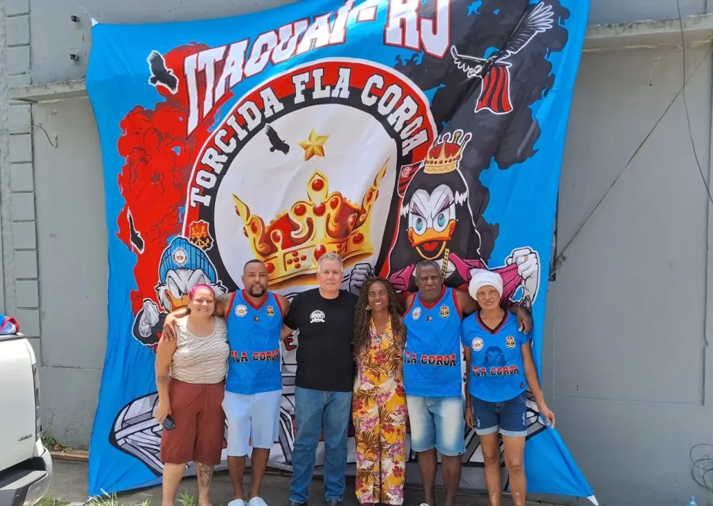 Pessoas posando em frente à bandeira da Torcida Fla Coroa