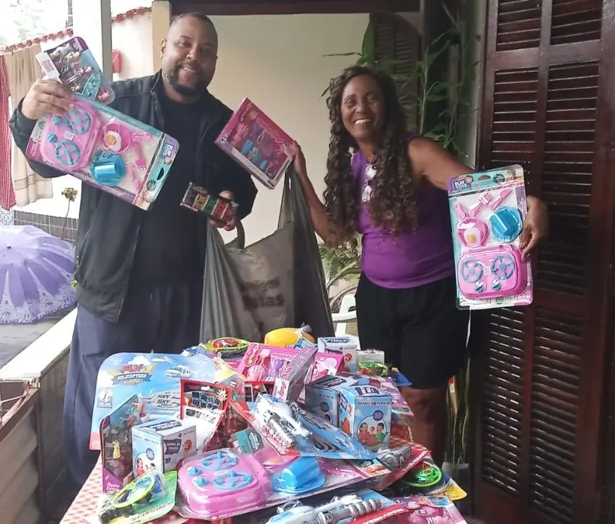 Reynaldo Dom e Wilma Martins exibindo brinquedos arrecadados