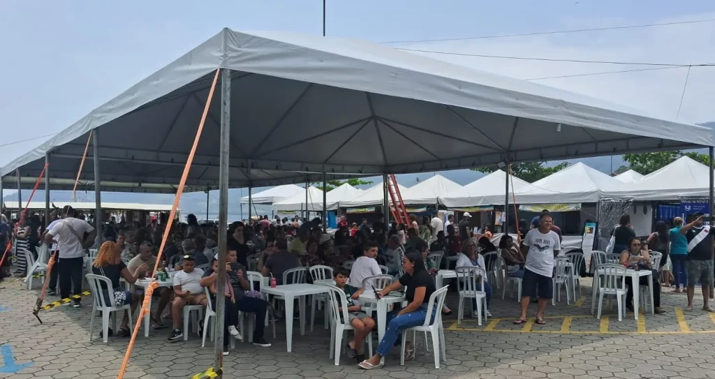 Várias pessoas sentadas sob uma tenda gigante