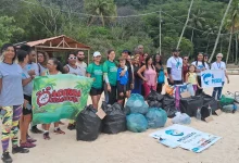 Várias pessoas posando na praia após o mutirão da limpeza