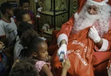 Crianças recebem presentes das mãos do Papai Noel durante a abertura da Programação Natalina