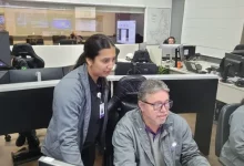 Jovem observando colega de trabalho teclando o computador