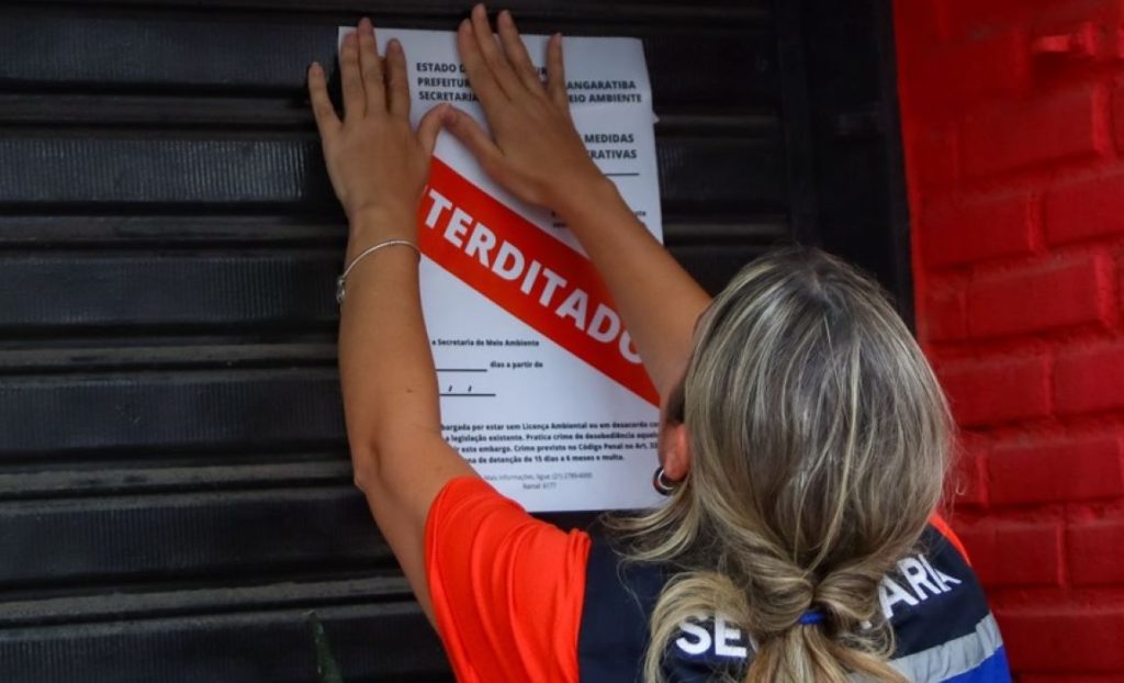 Fiscal da Secretaria de Meio Ambiente afixa aviso de interdição em estabelecimento