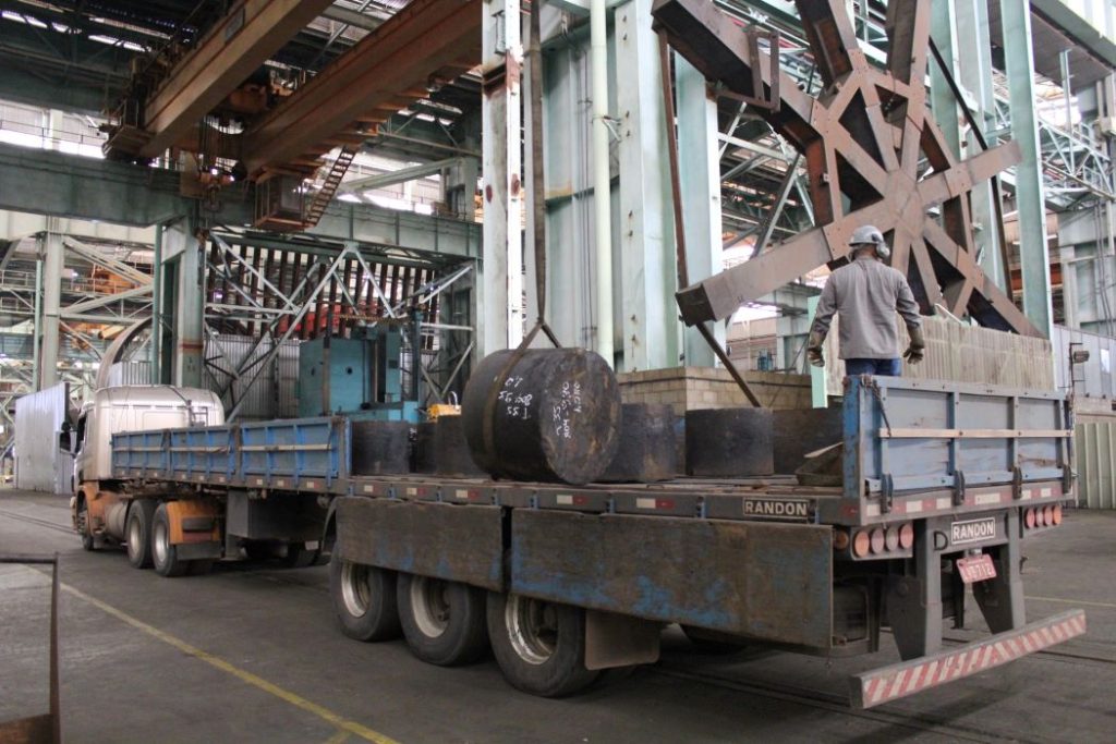 Movimentação e logística industrial no piso fabril da Nuclep, com transporte de componentes das estacas torpedo 