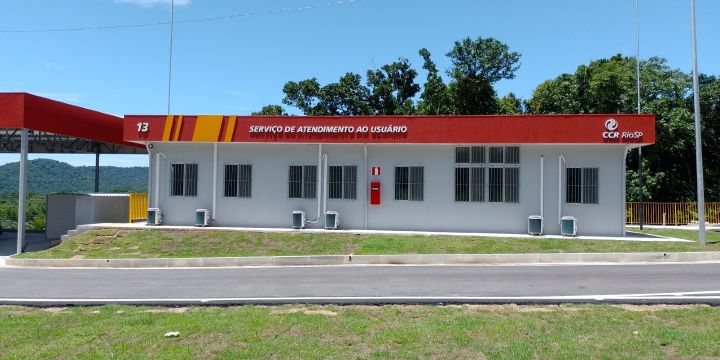 Base 13 da CCR RioSP na rodovia Rio-Santos, com fachada branca e marquise vermelha identificada como Serviço de Atendimento ao Usuário, em área cercada por vegetação em operação especial para o carnaval.