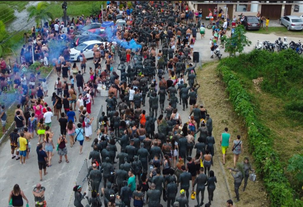 Foliões cobertos de lama desfilam pelas ruas de Paraty