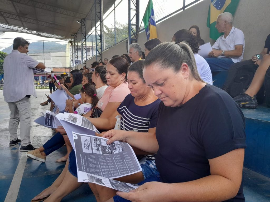 Pessoas numa arquibancada folheando jornais